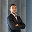 A man in a suit stands confidently in front of tall, classical columns, exuding professionalism and poise.